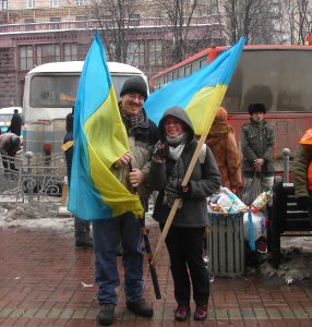 Photo of Brian and his wife Maryna at the demonstrations on Kreschatyk Street in downtown Kyiv, during the first week of the Orange Revolution in 2004. They are each carrying blue and yellow Ukrainian flags.