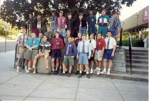 Photo of 23 male scholars standing outside Mark Twain Hall, grouped around the retaining wall. All are wearing shorts, dress shirts and ties.